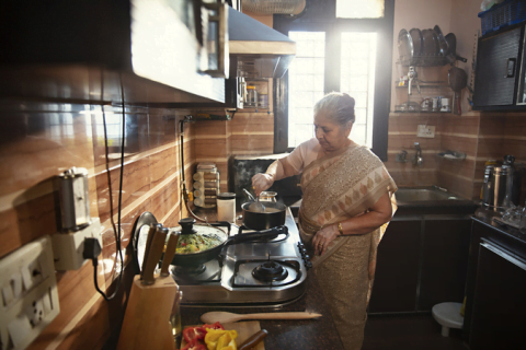 An older woman cooking a nutritious meal to improve her menopausal mental health.